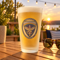 USAREUR-AF G2 Frosted Pint Glass with the G2 mark, filled, on a table at sunset